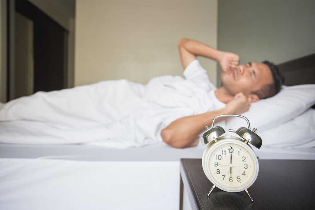 Apartment resident lying in bed with ears plugged for noisy neighbors